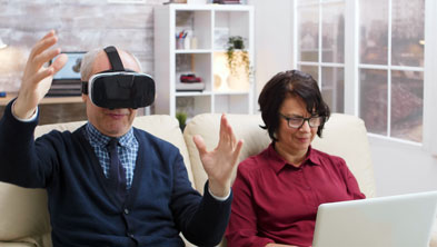 Zwei ältere Personen sitzen auf der Couch, schauen in den PC und durch eine VR-3D-Brille; Copyright Panthermedia