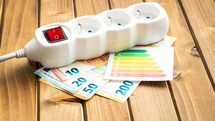 Mehrfachsteckdose liegt auf Geldscheinen und der Energielabel-Skala